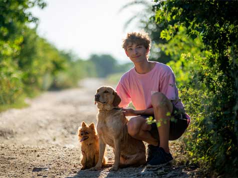 A girl carrying her brown poodle
